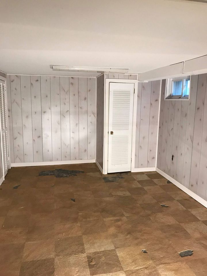 An empty room with a white door and a small window nearby, featuring a white ceiling with a tubelight fixed in place